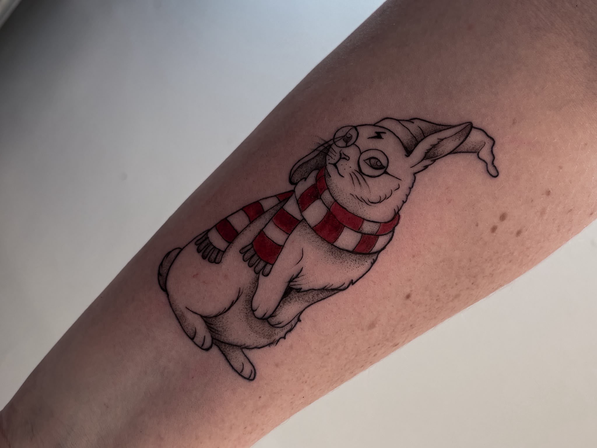 Illustratives Katzen-Tattoo mit Wintermütze und rot-weißem Schal